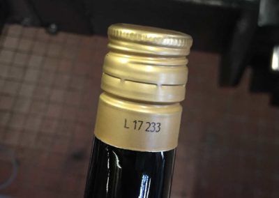 Coder les bouteilles I Les bouteilles de vin à capsules à vis sont identifiées avec un numéro de lot au niveau de la bague avec une imprimante jet d'encre dévié Ci-Series, adaptée aux cadences élevées. L'encre à séchage rapide a été retenue pour le contraste et l'adhérence élevée.